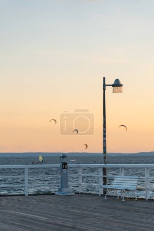 white empty wooden bench on pier by sea or ocean water, tranquility and serenity concept, calm sunset scene. High quality photo