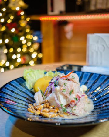 Photo for Peruvian ceviche served on a blue plate, with Christmas lights in the background - Royalty Free Image