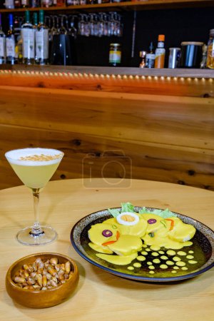 Photo for Papa a la huancaina, served with olives, hard-boiled egg and lettuce, accompanied by pisco sour - Royalty Free Image