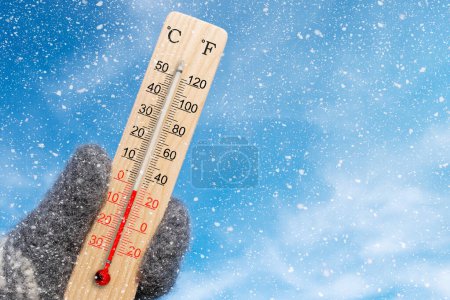 Téléchargez les photos : Wooden celsius and fahrenheit scale thermometer in hand. Ambient temperature minus 2 degrees celsius - en image libre de droit