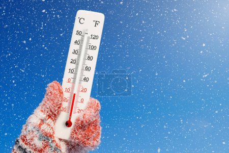 Foto de Termómetro blanco celsius y fahrenheit en mano. Temperatura ambiente menos 10 grados centígrados - Imagen libre de derechos