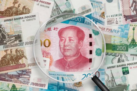 Téléchargez les photos : Billets en yuan chinois et en rouble russe. Collaboration Russie-Chine. Vue à travers loupe - en image libre de droit