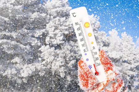 Téléchargez les photos : Vacances d'hiver avec neige. Thermomètre blanc à échelle celsius à la main. Température ambiante moins 25 degrés Celsius - en image libre de droit