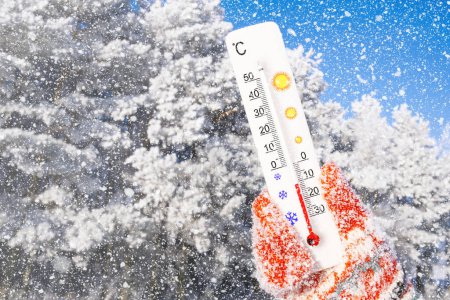 Winterurlaub mit Schnee. Weißes Thermometer in der Hand. Umgebungstemperatur minus 11 Grad Celsius
