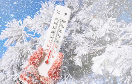 Weißes Celsius und Fahrenheit-Thermometer in der Hand. Umgebungstemperatur minus 16 Grad Celsius