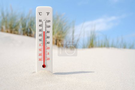 Hot summer day. Celsius and fahrenheit scale thermometer in the sand. Ambient temperature plus 30 degrees 