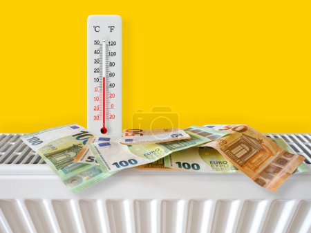 Euro-Banknoten am Heizkörper mit Thermometer. Energiekrise und teure Heizkosten für den Winter. Große Heizungs- und Gasrechnung. Thermometer zeigt plus 15 Grad warm