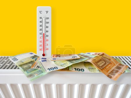 Euro-Banknoten am Heizkörper mit Thermometer. Energiekrise und teure Heizkosten für den Winter. Große Heizungs- und Gasrechnung. Thermometer zeigt plus 13 Grad warm
