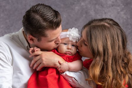Photo for Young dad and mom tenderly kiss their little girl. Love and tenderness of parents. Portrait. Close-up - Royalty Free Image