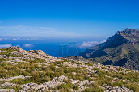 Erstaunliche Landschaften von Mallorca. Die Berge sind grün, das Meer ist blau und transparent. Sonniger Tag, Wolken über einem felsigen Grat. Mallorca, Spanien, Balearen