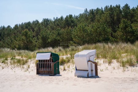 Am Sandstrand gibt es zwei Strandkorbs, die in verschiedene Richtungen ausgerichtet sind. Schutz vor Wind und Sonne. Ostsee, Deutschland.