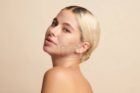 Foto de Hermosa mujer joven con piel limpia y fresca sobre fondo beige, Cuidado de la cara, Tratamiento facial, Cosmetología, belleza y spa, - Imagen libre de derechos