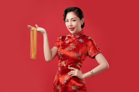 Foto de Festival de año nuevo chino, Hermosa mujer asiática joven con cheongsam tradicional vestido qipao con collares de oro sobre fondo rojo, - Imagen libre de derechos