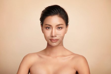 Foto de Hermosa mujer asiática joven con piel limpia y fresca sobre fondo beige, Cuidado de la cara, Tratamiento facial, Cosmetología, belleza y spa, Retrato de mujeres asiáticas. - Imagen libre de derechos