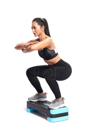 Photo for An asian woman is  working out  wearing the sport exercise suit with white background. - Royalty Free Image