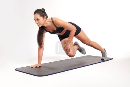 Photo for An asian woman is  working out wearing the sport exercise suit with white background, - Royalty Free Image