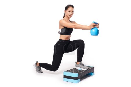 Photo for An asian woman is working out with kettlebell wearing the sport exercise suit with white background, - Royalty Free Image