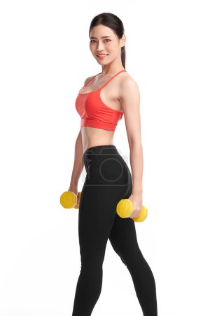 Photo for Sporty woman does the exercises with dumbbells on white background, Strength and motivation. - Royalty Free Image