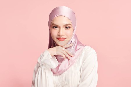 Foto de Hermosa joven mujer musulmana asiática usando un hiyab rosa sobre fondo rosa, Retrato de belleza árabe. - Imagen libre de derechos