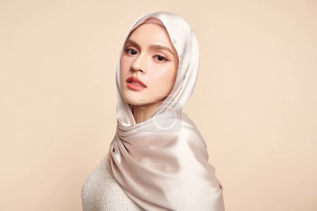 Téléchargez les photos : Belle jeune femme musulmane asiatique portant un hijab blanc sur fond beige, Portrait de Beauté Arabe. - en image libre de droit