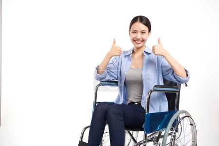 Téléchargez les photos : Belles jeunes femmes asiatiques avec un sourire heureux assis dans un fauteuil roulant sur fond blanc, concept de soins de santé, accident, assurance, assurance vie, bien-être, hôpital. - en image libre de droit