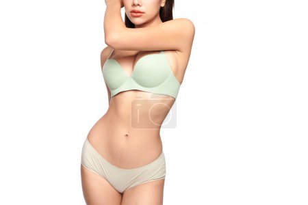 Foto de Confiado hermosa joven mujer asiática posando en ropa interior verde claro sobre fondo blanco, Cuerpo perfecto, - Imagen libre de derechos
