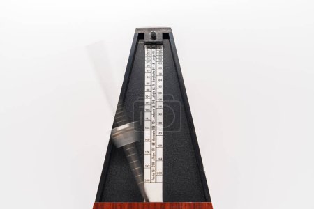 Téléchargez les photos : Old fashioned metronome with blurred arm indicating motion isolated on a white background - en image libre de droit