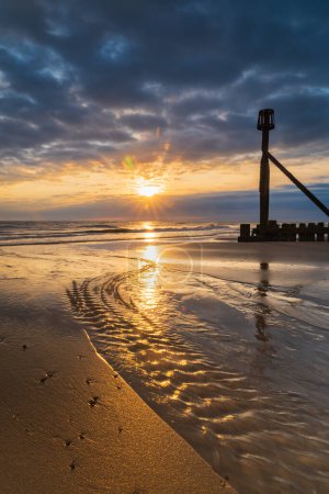 Photo for A portrait image of the sunrise on the beach in Mundesley, North Norfolk, UK - Royalty Free Image