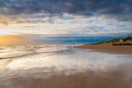 Photo for Tide receding at an empty beach in Mundesley, North Norfolk UK at sunrise - Royalty Free Image