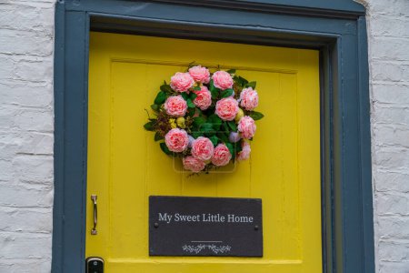 Téléchargez les photos : Porte d'entrée jaune avec un titre de plaque "My sweet little home" et une couronne rose - en image libre de droit