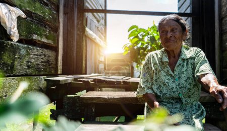 Ältere karibische Frau aus Nicaragua sitzt vor ihrem Holzhaus