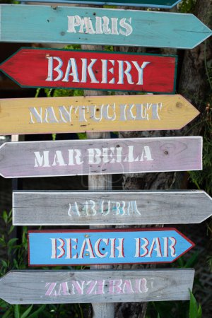 Foto de Signos de dirección pintados a mano de madera a muchos lugares en un resort. Colorida pieza de arte artesanal con un sentido local. - Imagen libre de derechos