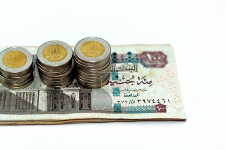 Photo for Pile of 100 EGP LE one hundred Egyptian pounds money banknotes with stacks of 1 LE EGP one pound coins isolated on white background, Egypt currency exchange rate concept,  selective focus - Royalty Free Image