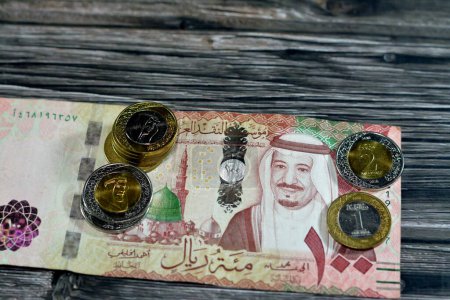 Photo for 100 SAR one hundred Saudi Arabia riyals cash money banknote with pile of Saudi riyal coins 1 and 2 riyals features king Salman Bin AbdulAziz Al Saud and King AbdulAziz, Saudi money exchange rate - Royalty Free Image