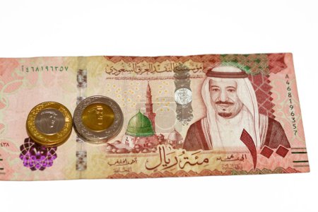 Photo for Obverse side of 100 SAR one hundred Saudi Arabia riyals cash money banknote feautures king Salman Bin AbdulAziz and Medina with change of Saudi riyal coins 1 and 2 riyals, Saudi money exchange rate - Royalty Free Image