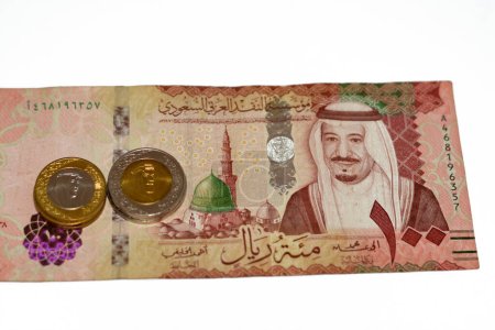 Photo for Obverse side of 100 SAR one hundred Saudi Arabia riyals cash money banknote feautures king Salman Bin AbdulAziz and Medina with change of Saudi riyal coins 1 and 2 riyals, Saudi money exchange rate - Royalty Free Image