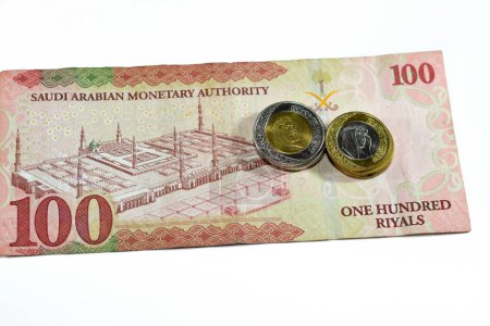 Photo for Reverse side of 100 SAR one hundred Saudi Arabia riyals cash money banknote features the prophet mosque in Medina with change of Saudi riyal coins 1 and 2 riyals, Saudi money exchange rate - Royalty Free Image