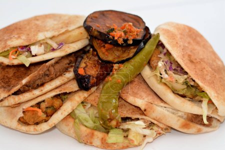 Foto de Berenjena frita en escabeche, pimientos verdes, sándwiches tradicionales egipcios de puré de habas, bolas de falafel crujientes fritas, dedos de papas fritas, sándwich de dinamita en pan sirio Shami - Imagen libre de derechos