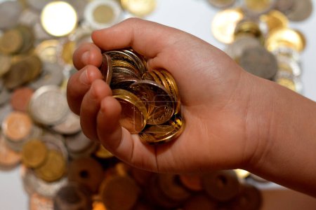 Foto de Una pila de monedas en la mano de un niño, pila de monedas de dinero egipcio en poder de un niño pequeño, el concepto de economía futura, la recogida de dinero para la caridad, y el ahorro de dinero - Imagen libre de derechos
