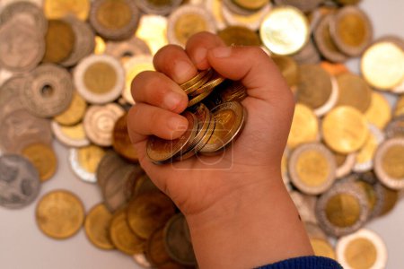 Photo for A pile of coins in the hand of a child, stack of Egyptian money coins held by a young child, the concept of economy future, collecting money for charity, and saving money - Royalty Free Image