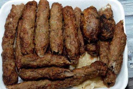 Photo for Arabic cuisine traditional food beef Kofta, kebab and tarb kofta shish which is minced meat wrapped in lamb fat charcoal grilled and served on flatbread, oriental grilled barbecued meat food - Royalty Free Image
