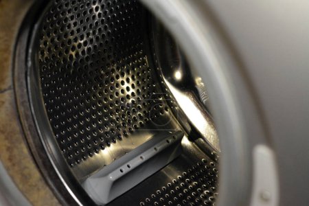 Téléchargez les photos : Tambour de machine à laver en acier inoxydable avec une porte ouverte de la rondelle, entretien de la machine à laver, concept de fixation et de remplacement, mise au point sélective - en image libre de droit