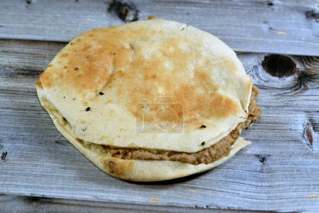 Foto de Puré de habas mezcladas con aceite, sésamo tahini, comino, especias en un pan de pita siria Shami, enfoque selectivo de los tradicionales sándwiches de frijol egipcio populares aislados - Imagen libre de derechos