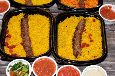 Photo for Arabic cuisine traditional food beef  Kofta, kebab and tarb kofta shish which is minced meat with Basmati rice and raisins, oriental grilled barbecued meat food with long yellow rice, selective focus - Royalty Free Image