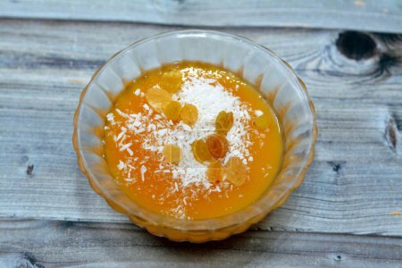 Photo for Ramadan sweet Arabian dessert recipe made from Qamar Al-Din (dried and cooked apricot fruit past) cooked with water, corn starch, sugar and vanilla, usually covered with raisins and shredded coconut - Royalty Free Image