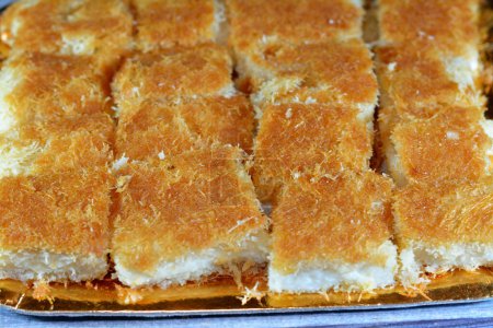 Téléchargez les photos : Un dessert traditionnel du Moyen-Orient Knafeh Konafa fait avec de la pâte filée kataifi, trempé dans un sirop de miel de sucre sucré, stratifié avec du fromage, de la crème caillée ou fouettée, dessert égyptien Ramadan kunafa - en image libre de droit