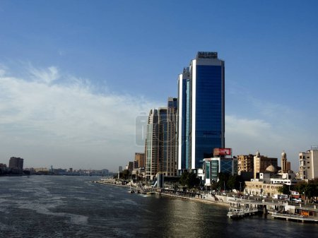 Photo for Cairo, Egypt, April 16 2023: The river Nile of Egypt  with modern buildings and bridges along the Nile bank and the Egyptian walk on the river coast at the daylight of Cairo city, selective focus - Royalty Free Image