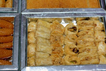 Foto de Diferentes tipos de dulces orientales de Baklava cubiertos y rellenos de pistachos, Sekerpare (Romoosh el Set), galletas de sémola, dedos de Zainab o dedos de anís vidriados, Knafeh Konafa relleno con crema - Imagen libre de derechos