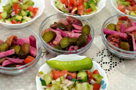 Photo for Traditional Arabic green salad with slices of cucumber and tomatoes mixed together and a green chili pepper and marinated vegetables (Torshi) or mixed pickled vegetables of sliced cucumbers, carrots - Royalty Free Image