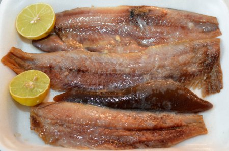 Stücke von heiß geräuchertem Heringsfilet und weichem Rogen mit Öl und Zitrone in einem Teller zubereitet, selektiver Schwerpunkt der Fischküche von Heringen Fisch bereit zum Servieren